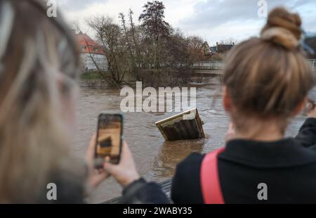 Marburg, Germania. 3 gennaio 2024. Due studenti scattano una foto del Lahn di Marburgo, che ha fatto scoppiare le sue banche. La situazione delle inondazioni in Assia è tesa. Credito: Nadine Weigel/DPA/Nadine Weigel/dpa/Alamy Live News Foto Stock