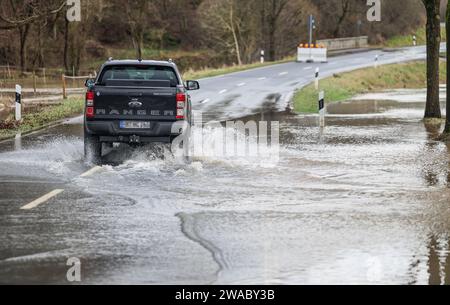 Marburg, Germania. 3 gennaio 2024. Un'auto guida su una strada allagata. Il Lahn vicino a Marburgo ha fatto esplodere le sue banche. La situazione delle inondazioni in Assia è tesa. Credito: Nadine Weigel/DPA/Nadine Weigel/dpa/Alamy Live News Foto Stock