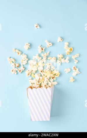 Un secchio a strisce di popcorn su sfondo azzurro, vista dall'alto e spazio per la copia. Formato verticale. Foto Stock