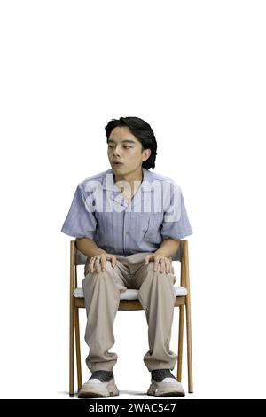 Un tizio con una camicia blu, su uno sfondo bianco, è seduto su una sedia Foto Stock