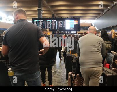 Londra Inghilterra Regno Unito 3 gennaio 2024 i passeggeri attendono informazioni sulla partenza dei treni dalla stazione ferroviaria di Londra Euston tramite le schede di partenza del Customer Information System (CIS). I pannelli di partenza sono prodotti da Infotec. Si tratta di un design a LED RGB a matrice completa. I display sono in grado di visualizzare avvisi grafici avanzati in un formato flessibile e dinamico. I sistemi di visualizzazione sono collegati a sistemi di informazione dei treni in tempo reale per consentire l'aggiornamento automatico. La stazione è gestita da Network Rail ©Ged Noonan/Alamy Foto Stock