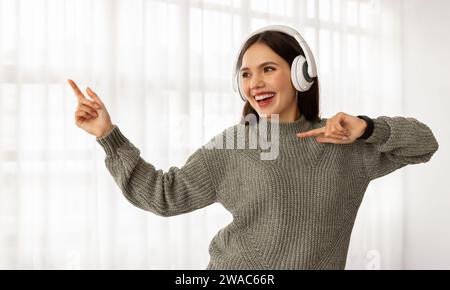Giovane donna gioiosa che ascolta musica e danza Foto Stock