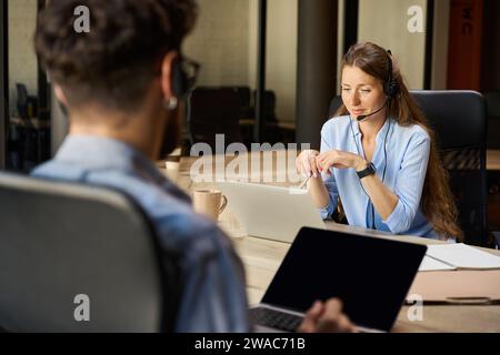 Operatori di call center caucasici che utilizzano computer portatili in un ufficio di coworking Foto Stock