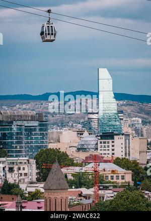 Vista sul grattacielo di vetro dell'hotel Biltmore e una funivia di Tbilisi nella città vecchia di Tbilisi, Georgia Foto Stock