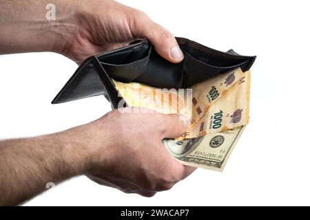 Mano con portafoglio che mostra banconote in dollari e banconote in peso argentino Foto Stock