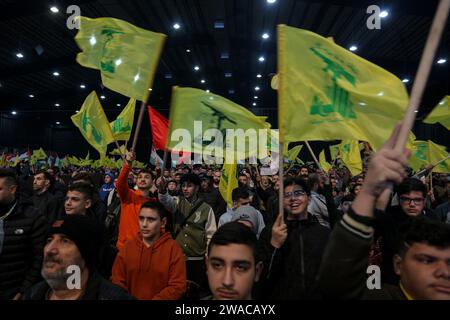 Beirut, Libano. 3 gennaio 2024. I sostenitori pro-iraniani di Hezbollah partecipano a una messa in quanto il Segretario generale di Hezbollah Hassan Nasrallah sembra tenere un discorso televisivo in occasione del quarto anniversario dell'assassinio di Abu Mahdi al-Mohandes, vice capo della milizia irachena di Hashd al-Shaabi, e il comandante della forza Quds iraniana Qasem Soleiman da un drone americano in Iraq nel 2020. Crediti: Marwan Naamnai/dpa/Alamy Live News Foto Stock