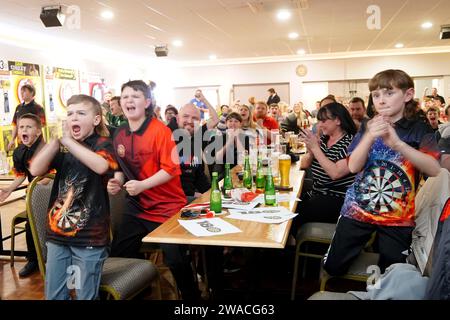 I membri del club locale di Luke Littler, la St Helen's Darts Academy, lo guardano giocare contro Luke Humphries nella finale del World Darts Championship. Il sedicenne è il giocatore più giovane di sempre a raggiungere il decisivo in un viaggio memorabile all'Alexandra Palace, ma dovrà affrontare il test più duro di sempre contro il nuovo numero uno del mondo mentre tenta di diventare il più giovane vincitore di sempre. Data foto: Mercoledì 3 gennaio 2024. Foto Stock