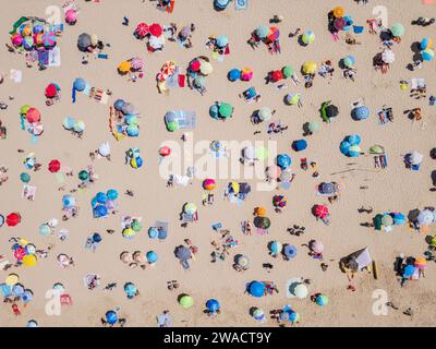 Vista dall'alto verso il basso delle persone che si rilassano sulla spiaggia in una giornata di sole a Costa da Caparica, vicino a Lisbona, Portogallo. Foto Stock