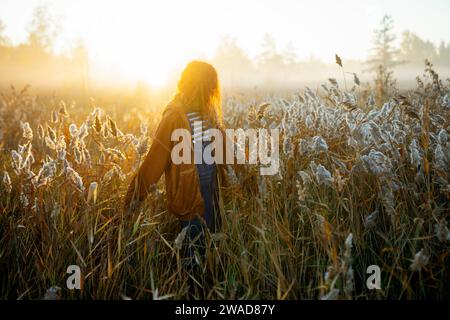 Giovane donna che cammina in campo all'alba Foto Stock