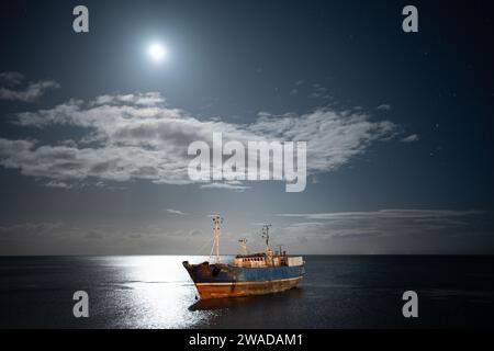 nave abbandonata sotto la luna Foto Stock