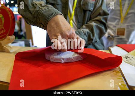 Un maestro del tè sta avvolgendo un pezzo di torta PU'er tea in carta rossa Foto Stock