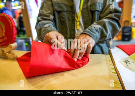 Un maestro del tè sta avvolgendo un pezzo di torta PU'er tea in carta rossa Foto Stock