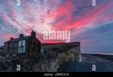 Spettacolare cielo all'alba sopra i precari cottage sul bordo della scogliera di Birling Gap a sud della costa orientale del Sussex, Inghilterra sud-orientale, Regno Unito Foto Stock