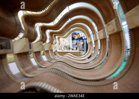 ZAOZHUANG, CINA - 4 GENNAIO 2024 - Un operaio esperto produce prodotti per chitarra in un laboratorio a Zaozhuang, provincia dello Shandong, Cina, 4 gennaio 2024. Foto Stock