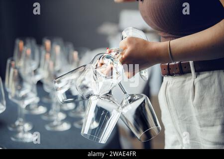 Una cameriera prende qualche bicchiere di vino vuoto dal tavolo del bar, da vicino senza faccia. Servizio ristorante e personale. Foto Stock