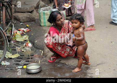 Una madre bagna sua figlia sulla strada, Calcutta, Bengala Occidentale, India Foto Stock