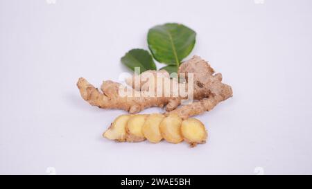 Un primo piano di pezzi disposti di zenzero e foglie di lime isolate su sfondo bianco Foto Stock