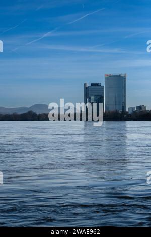 Bonn, Germania - 17 dicembre 2023: Veduta del fiume Reno gonfio, del Campus delle Nazioni Unite e della Torre della posta sullo sfondo a Bonn, Germania Foto Stock