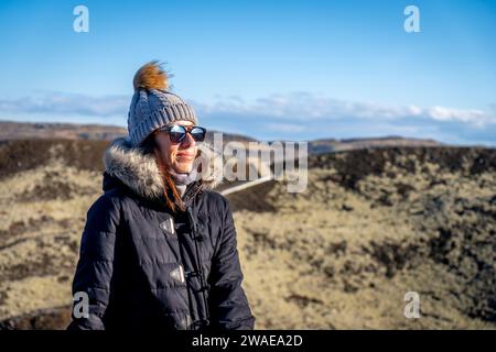 Un uomo caucasico adulto sorridente in piedi su una vetta rocciosa della montagna con cappello protettivo e occhiali da sole Foto Stock