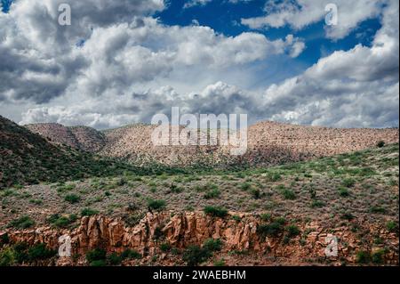 Una vista panoramica di un paesaggio montuoso coperto di arbusti verdi sotto un cielo blu nuvoloso Foto Stock
