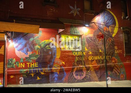 Un muro di mattoni di un edificio coperto di graffiti, illuminato di notte a New York Foto Stock