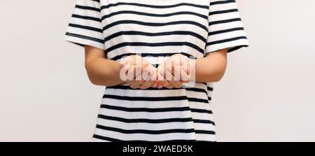 La donna con una maglietta a righe le tiene le mani davanti con i palmi alzati. Foto Stock