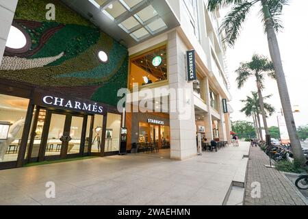 HO CHI MINH CITY, VIETNAM - 29 MARZO 2023: Vista a livello della strada del caffè Starbucks e del negozio Charmes a ho chi Minh City al crepuscolo. Foto Stock