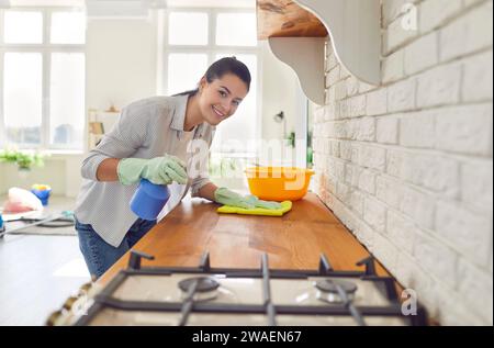 La casalinga sorridente pulisce la polvere in cucina Foto Stock