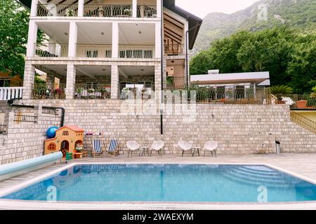 Sedie in vimini con tavoli in piedi davanti alla piscina vicino a un hotel privato Foto Stock