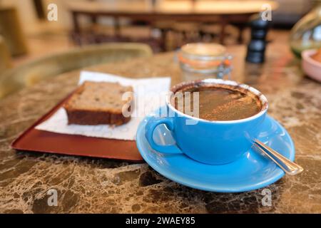 Una tazza di caffè cappuccino con una fetta di torta in una caffetteria nel Regno Unito Foto Stock