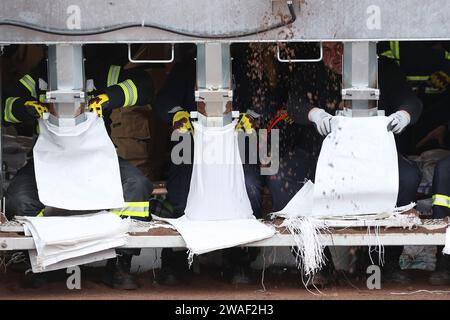 Sangerhausen, Germania. 4 gennaio 2024. Gli assistenti dei vigili del fuoco riempiono i sacchi di sabbia a macchina. Lo stesso giorno, il Cancelliere federale Scholz e il Ministro della Sassonia-Anhalt, il Presidente Haseloff, visiteranno l'area alluvionale intorno all'Helme e parleranno con i volontari. Crediti: Jan Woitas/dpa/Alamy Live News Foto Stock