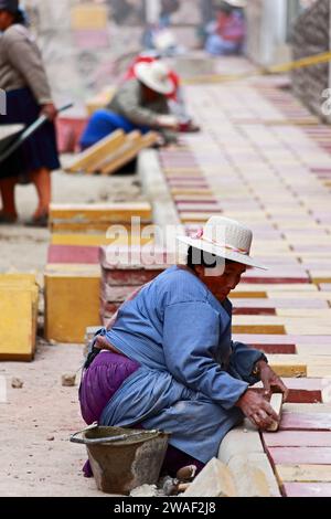 Donne Quechua locali che lavorano a un progetto di lavori pubblici che posa un nuovo marciapiede/marciapiede in mattoni, Potosi, Bolivia Foto Stock