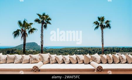 Una terrazza solarium bianca e soleggiata situata in una lussureggiante oasi tropicale a Ibiza, Spagna Foto Stock