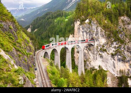Treno rosso svizzero sul viadotto in montagna per un giro panoramico Foto Stock
