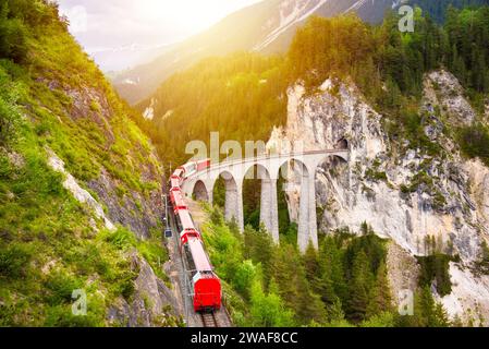 Treno rosso svizzero sul viadotto in montagna per un giro panoramico Foto Stock