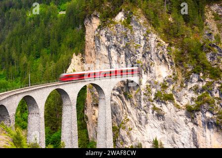 Treno rosso svizzero sul viadotto in montagna per un giro panoramico Foto Stock