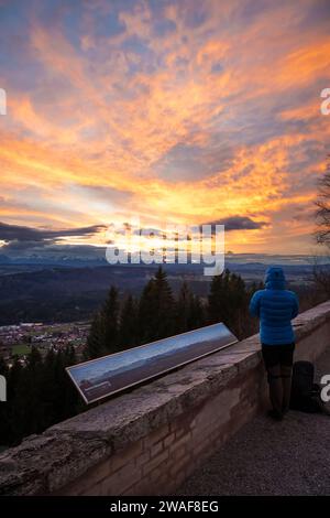 Una persona accanto alla mappa panoramica guarda il panorama alpino da Hohenpeissenberg al tramonto, Baviera, Germania Foto Stock