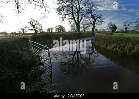 Wrexham, Regno Unito. 4 gennaio 2024. Vista di una strada allagata che conduce alla fattoria nel Galles nord-orientale, che mostra l'impatto della recente tempesta Henk. Gli avvisi di alluvione per l'area di Bangor-on-Dee nel Galles nord-orientale sono in funzione da martedì mattina. Risorse naturali Wales avvertì che le strade principali potevano inondare. Henk era l'ottavo tempesta in tre mesi. È stato nominato molto più tardi del solito - ore prima del suo impatto - perché era piccolo e stava ancora sviluppando. (Foto di Andrew McCoy/SOPA Images/Sipa USA) credito: SIPA USA/Alamy Live News Foto Stock