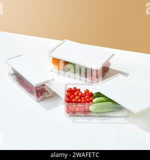 Contenitore per alimenti in vetro con coperchio in legno riempito con frutta e verdura sfondo color crema Foto Stock