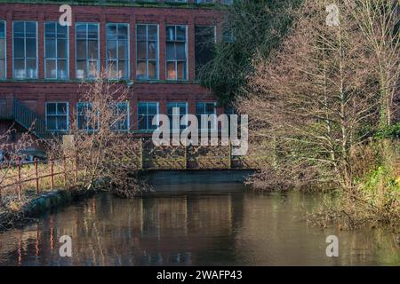 Un vecchio ponte di ferro arrugginito sopra la corsa dei mulini a East Mill a Belper, Derbyshire, Inghilterra Foto Stock