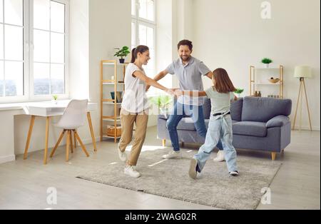 La famiglia felicissima con un bambino a casa passa attivamente del tempo insieme ballando a ritmo di musica. Foto Stock