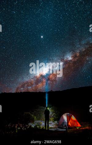 Silhouette di un uomo in piedi accanto a una tenda da campeggio che osserva la via Lattea. Foto Stock