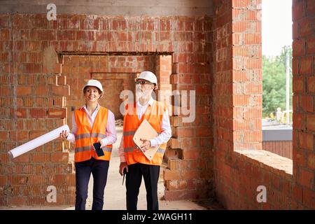 Gioioso ispettore architettonico e caposquadra che ispeziona l'interno dell'edificio Foto Stock