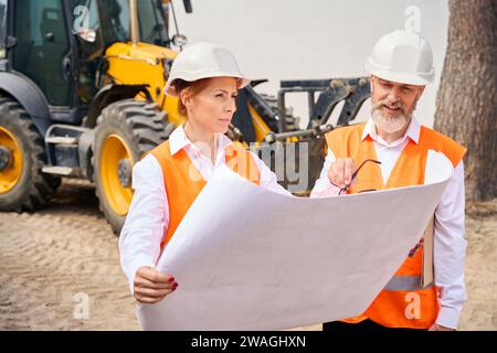 Ispettore edile e appaltatore che utilizzano progetti durante l'ispezione Foto Stock