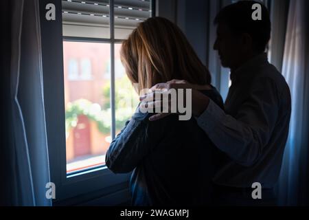 Uomo che conforta sua moglie con depressione e tristezza e con la mano sulla spalla. Foto Stock