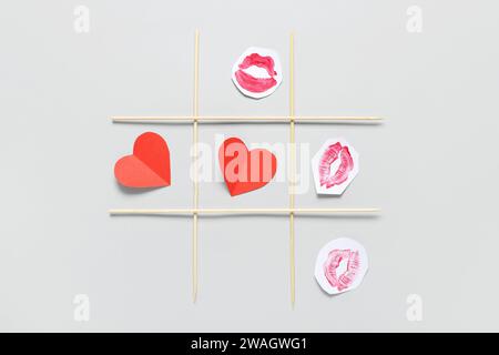 TIC tac Toe game con cuori di carta e baci di rossetto su sfondo chiaro. Festa di San Valentino Foto Stock