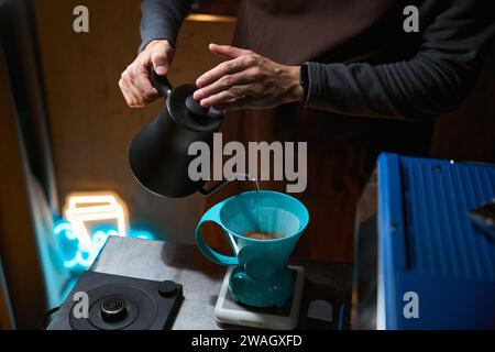 Barista che versa acqua calda sul filtro con caffè macinato nell'imbuto Foto Stock