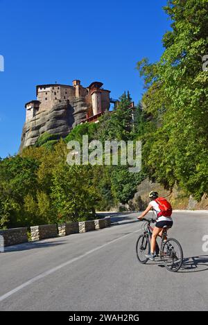 Motociclista sulla strada di fronte al monastero di Roussanou, ai monasteri di Meteora, alla Grecia, alla Tessaglia Foto Stock