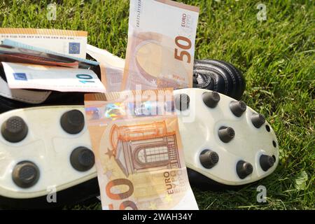 Scarpa da calcio con euro su un campo da calcio, immagine simbolica del calcio professionistico Foto Stock