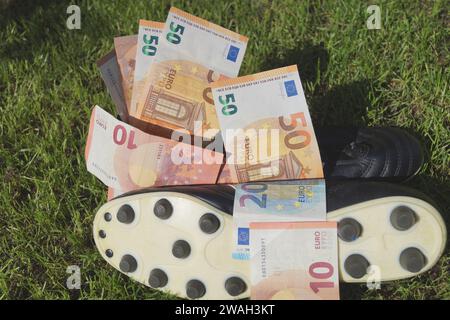 Scarpa da calcio con euro su un campo da calcio, immagine simbolica del calcio professionistico Foto Stock